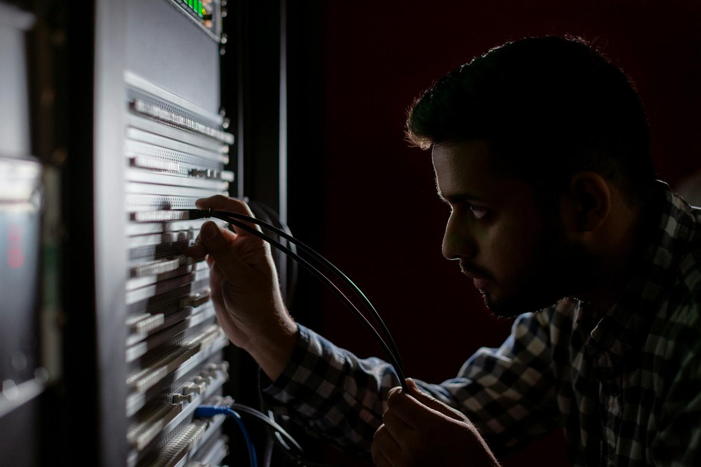 Network technician patching cables in an equipment rack