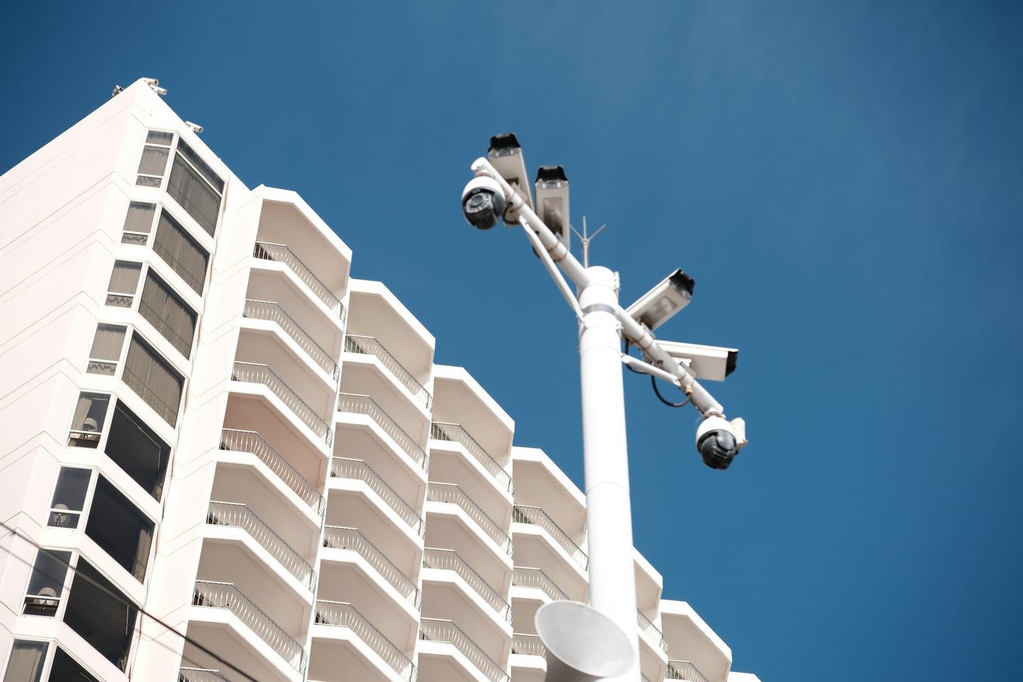 Security cameras mounted on a pole beside a high-rise building