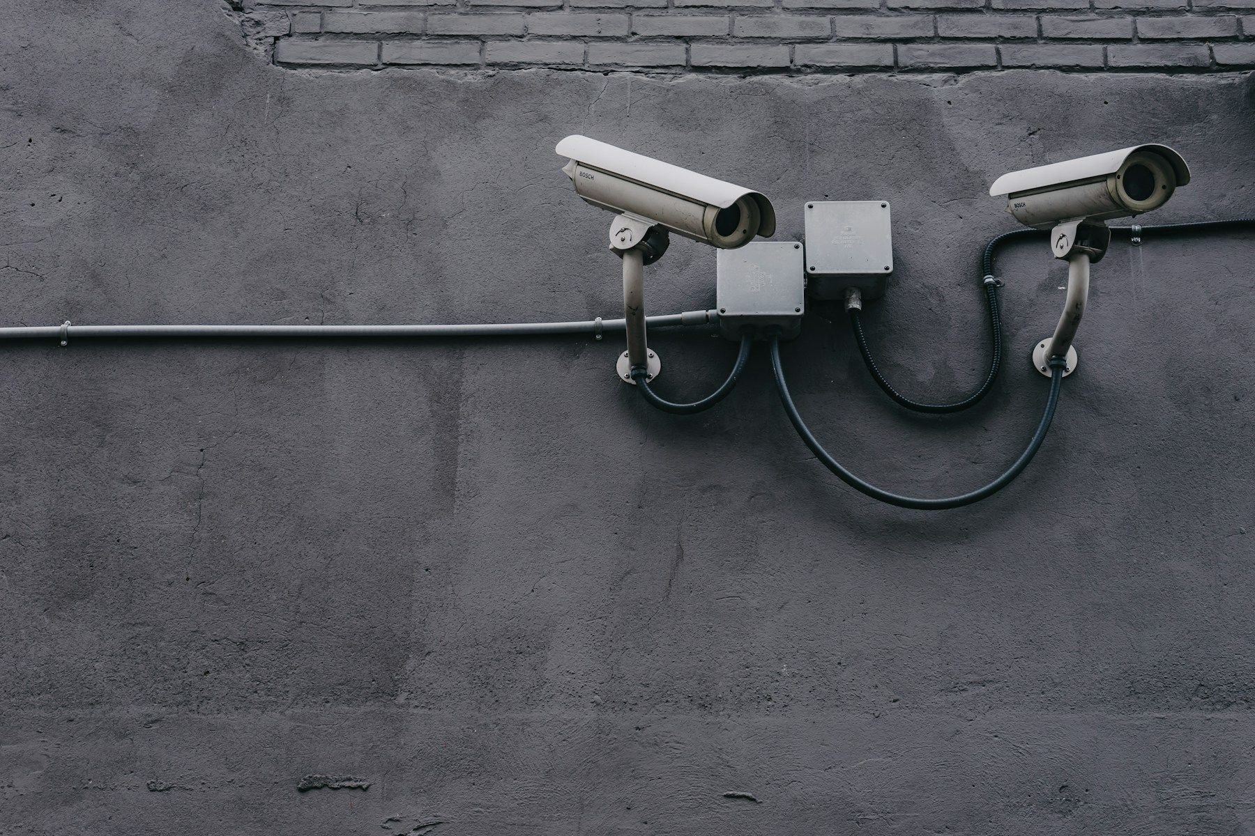 Two surveillance cameras mounted on a grey wall