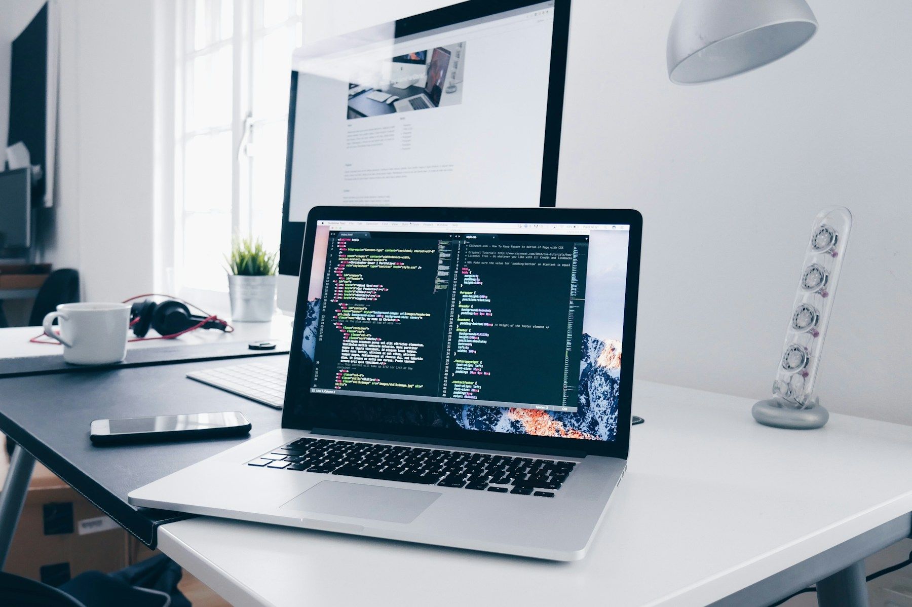 Laptop showing code on a bright developer desk